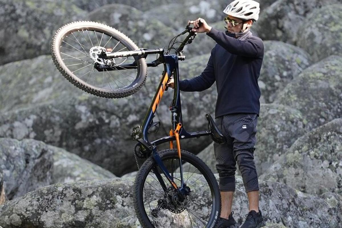 a man holding a bike on top of rocks