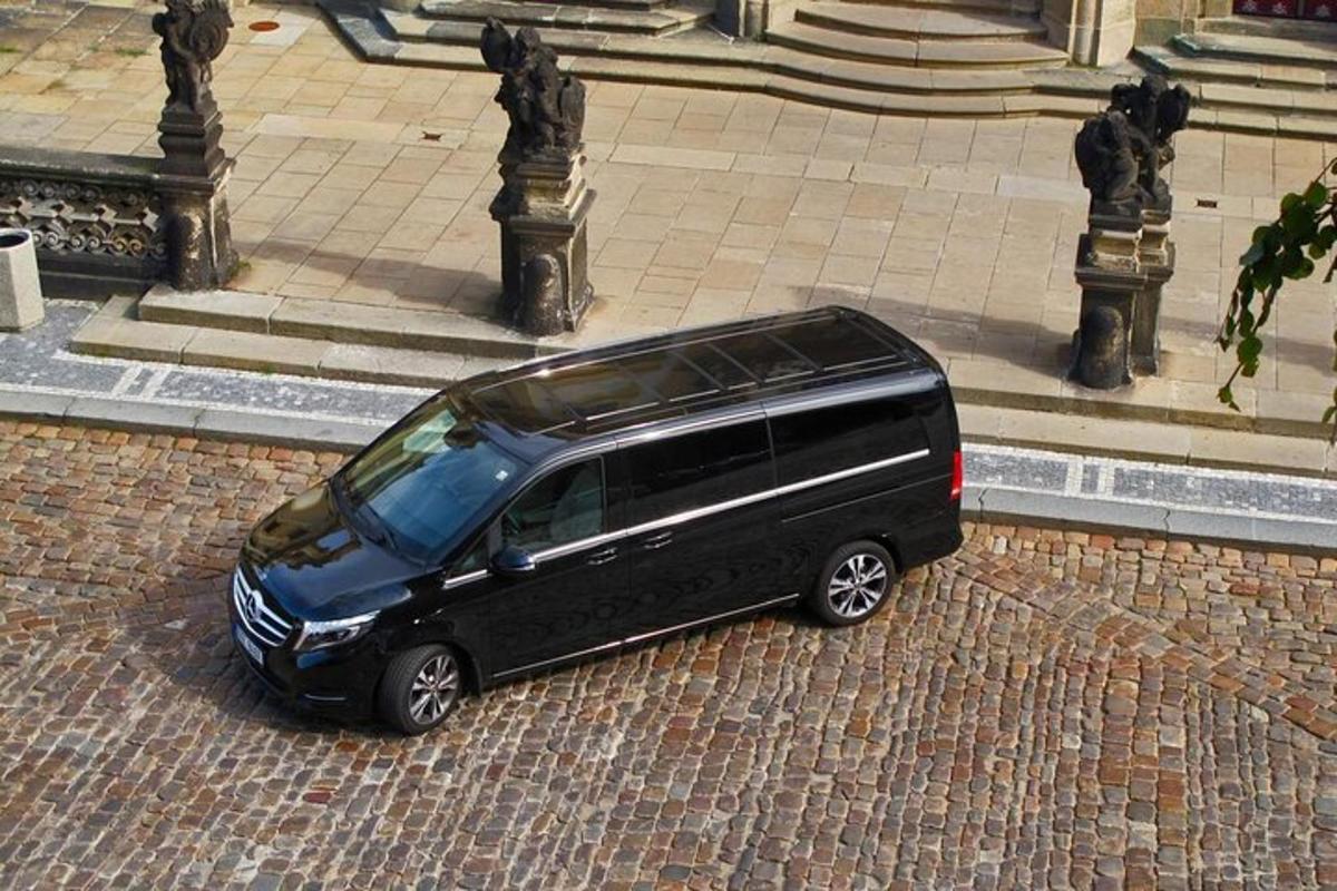 uma van preta estacionada em uma rua de tijolos