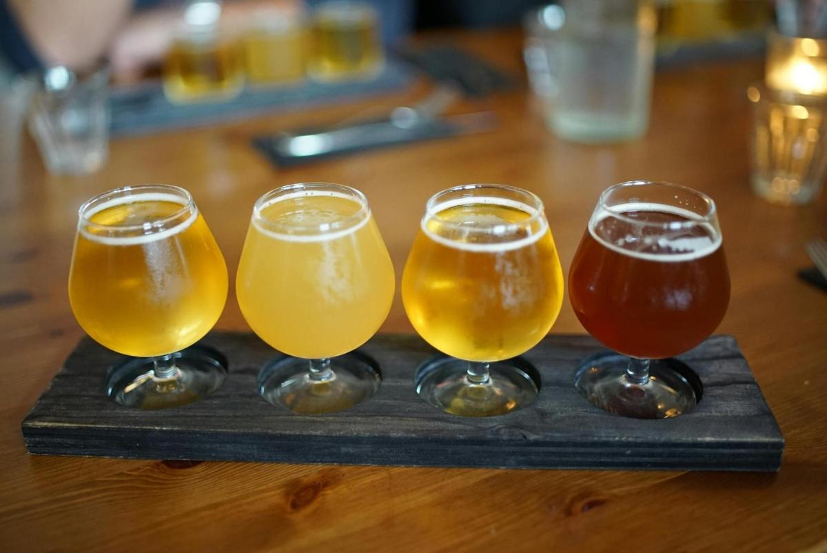 quatre gots de cervesa en una safata sobre una taula