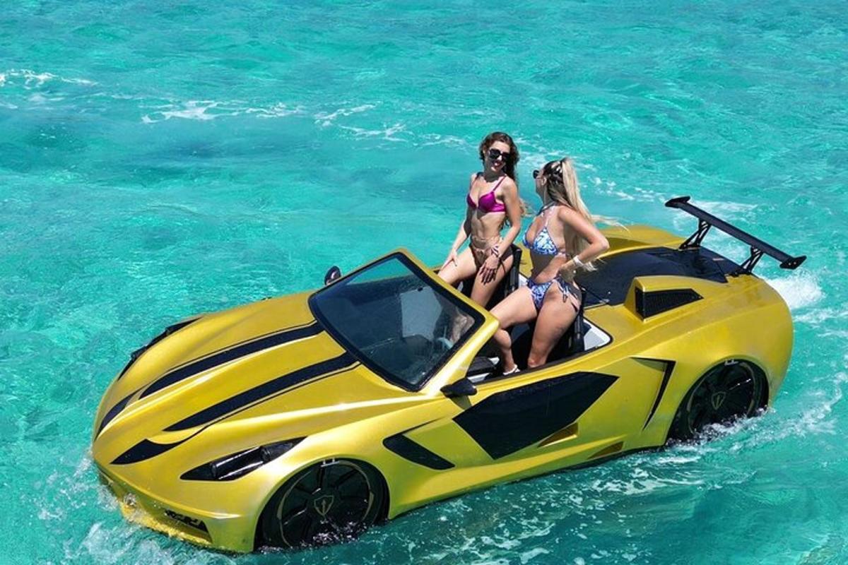 two girls are sitting on a yellow super car in the water