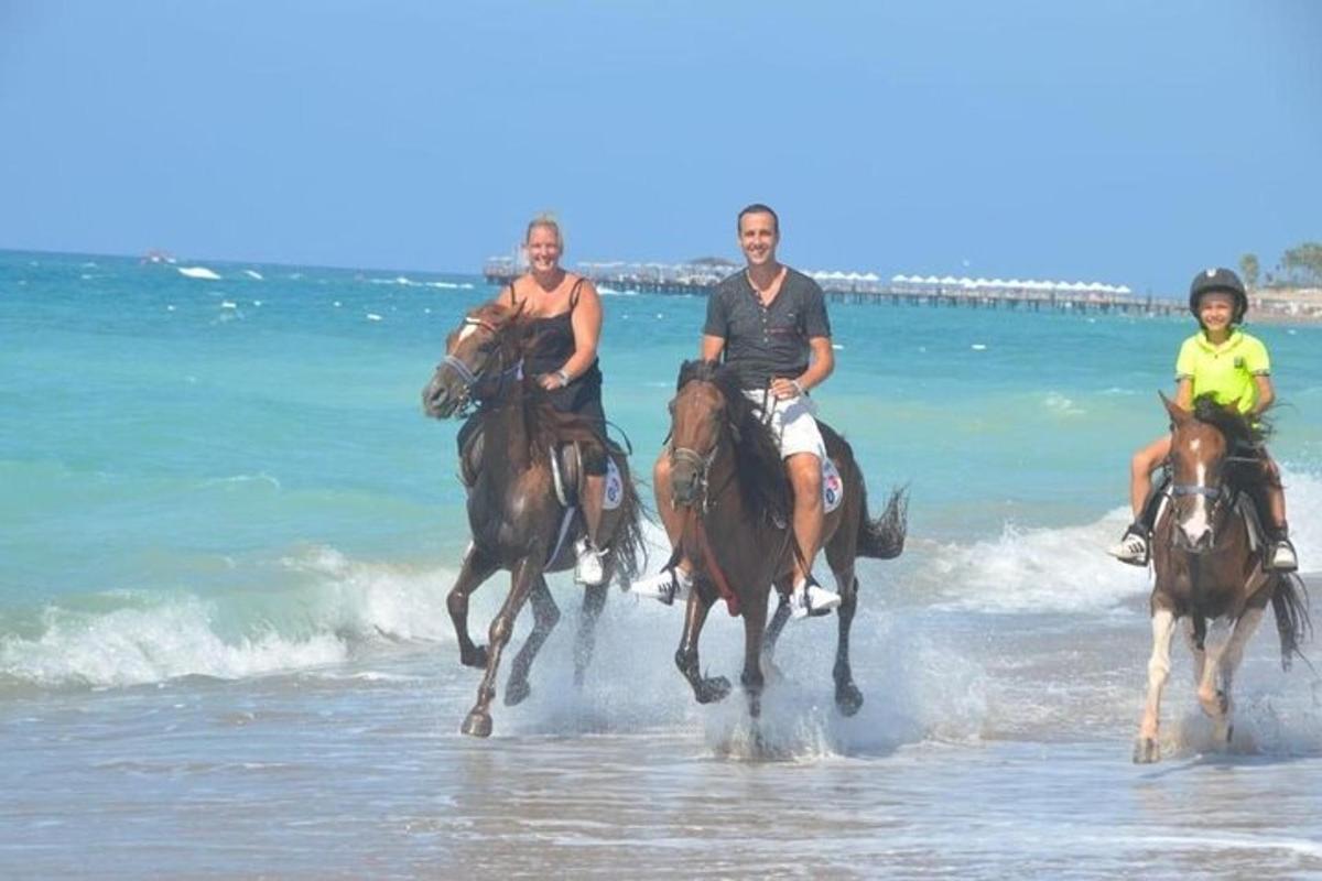 a group of people riding horses on the beach