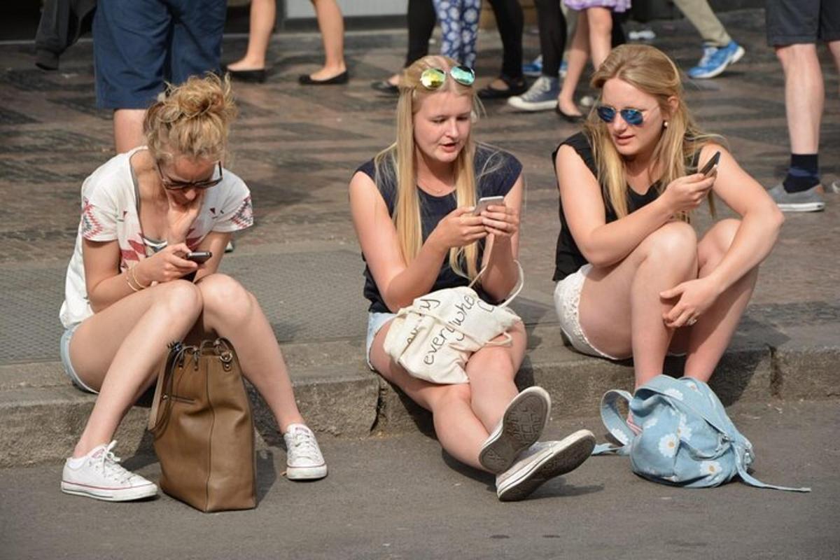 trei fete stând pe trepte și uitându-se la telefoanele lor mobile