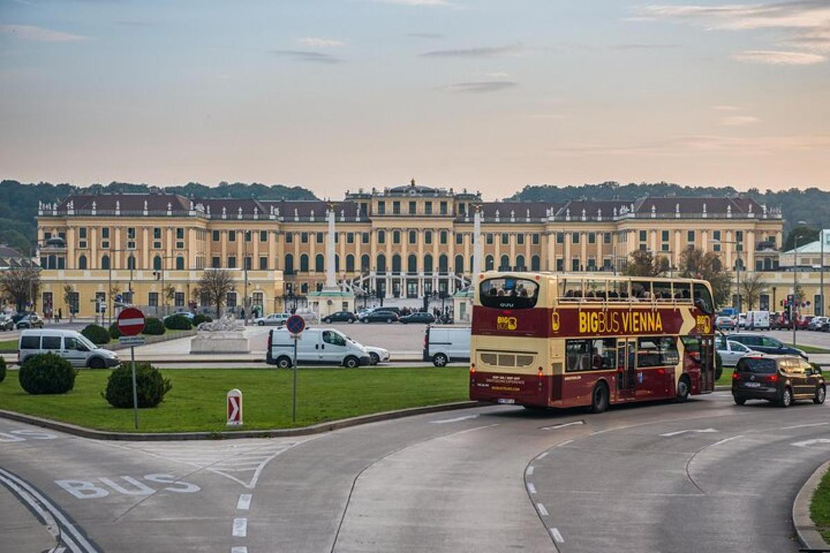 kahekordne buss sõidab mööda teed hoone ees