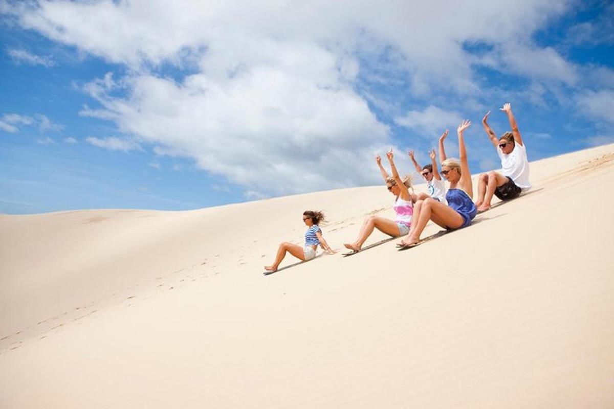 a group of people sitting on top of a sand dune