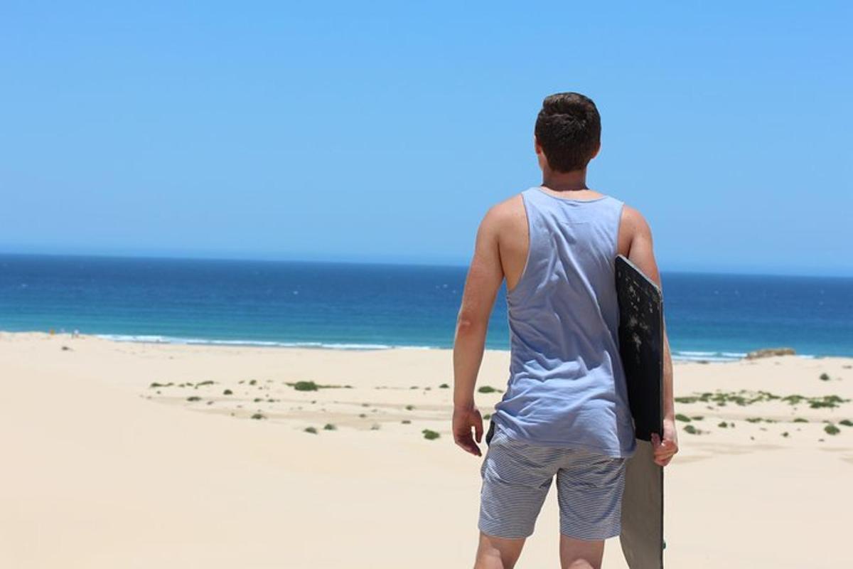 a man standing on the beach holding a surfboard