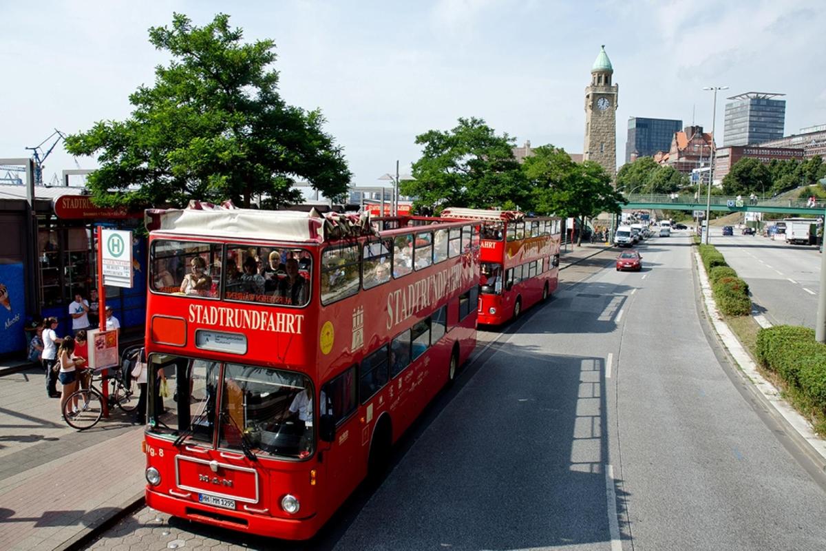 dva červené dvoupatrové autobusy jedoucí po ulici