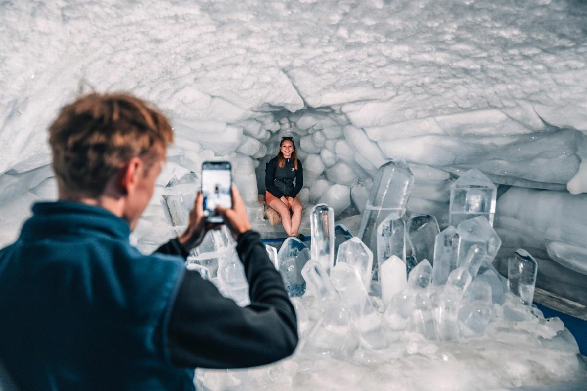 a man taking a picture of a woman in an ice cave