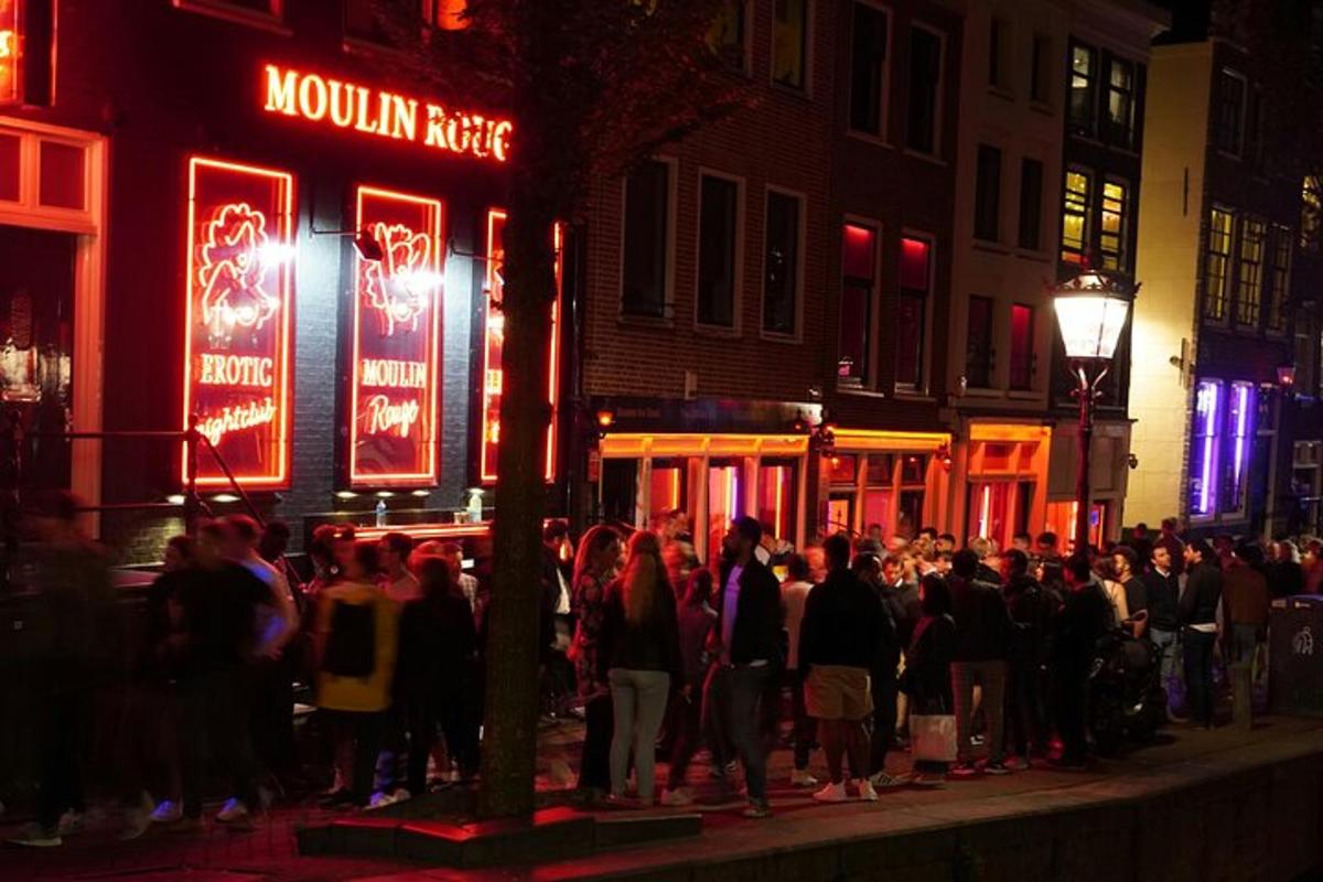 Una multitud de personas paradas en una calle por la noche