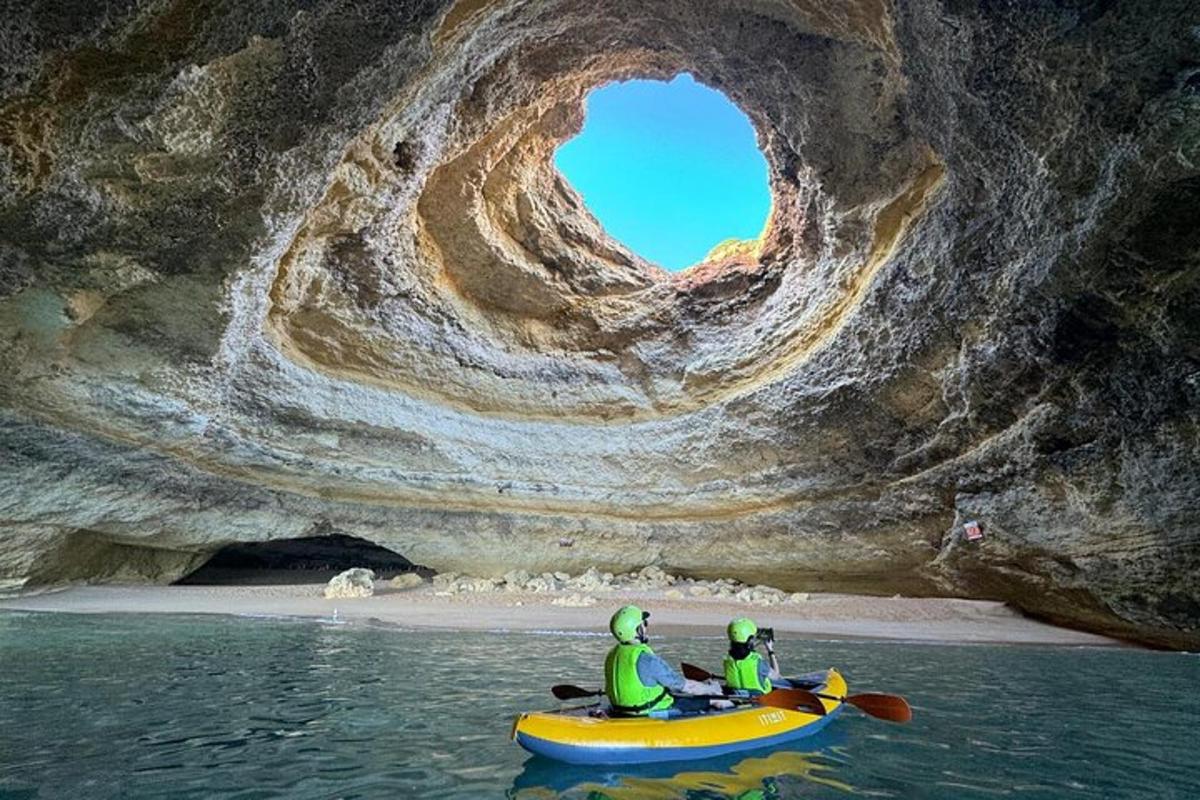 zwei Personen in einem Kajak vor einer Höhle
