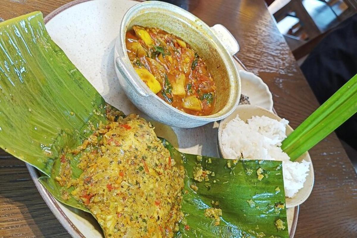 un piatto di cibo con una ciotola di zuppa e una foglia di banana