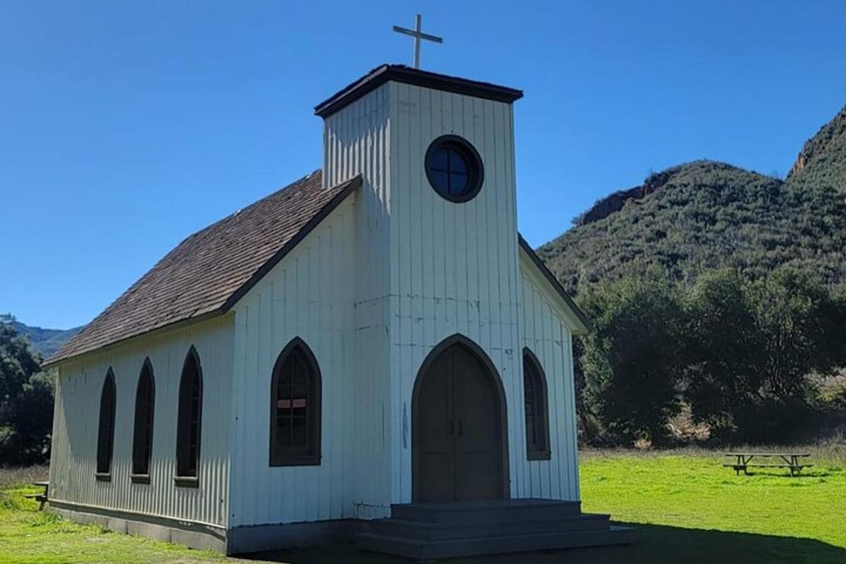 una piccola chiesa bianca con una torre dell'orologio in un campo