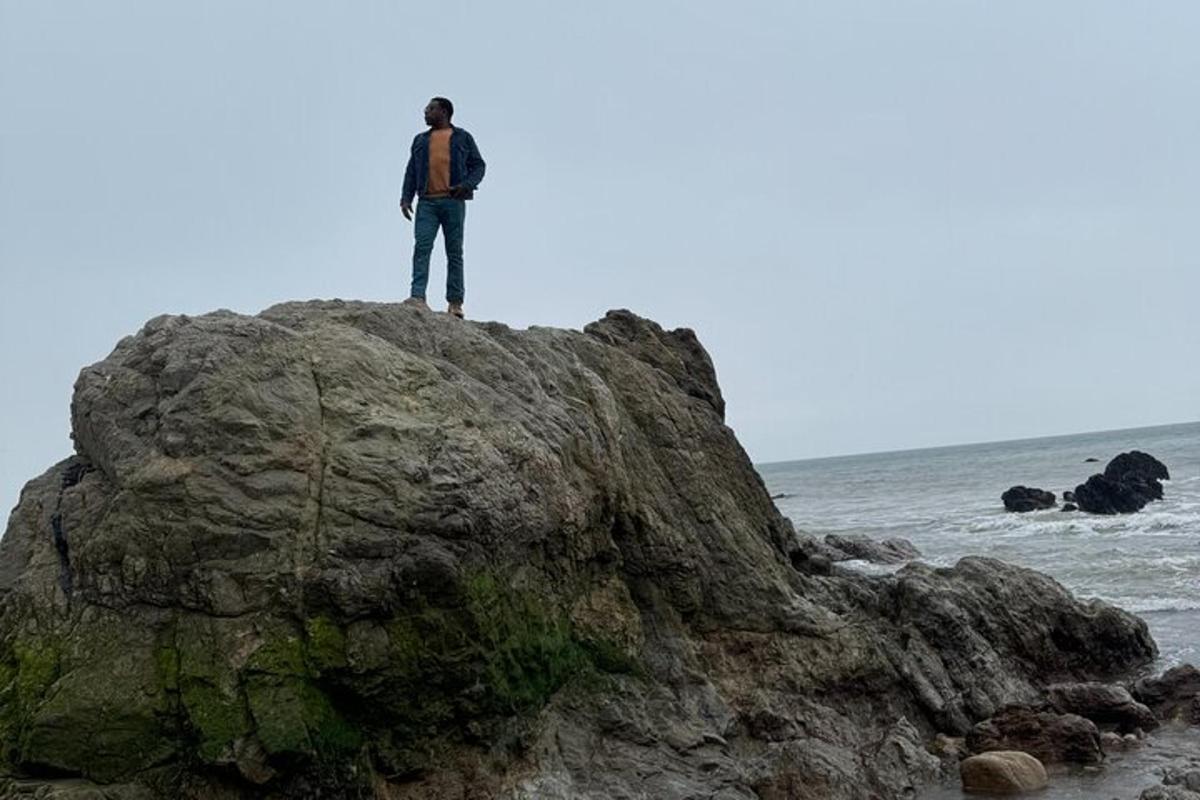 un uomo in piedi su una roccia sulla spiaggia