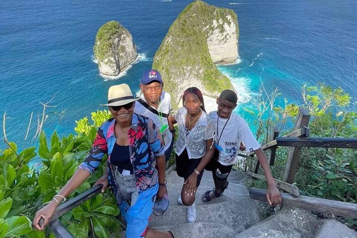 a group of people standing on a ledge near the ocean