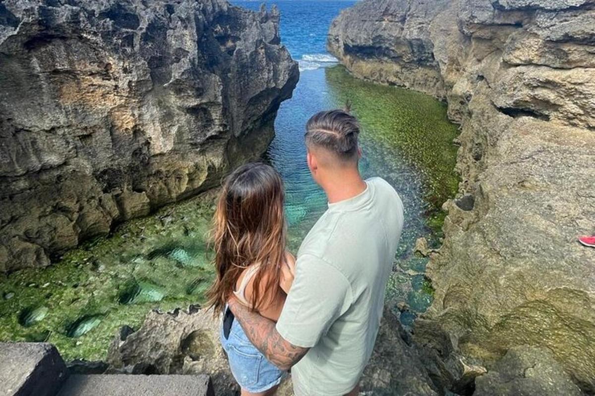 a man and woman standing on a cliff looking at the water