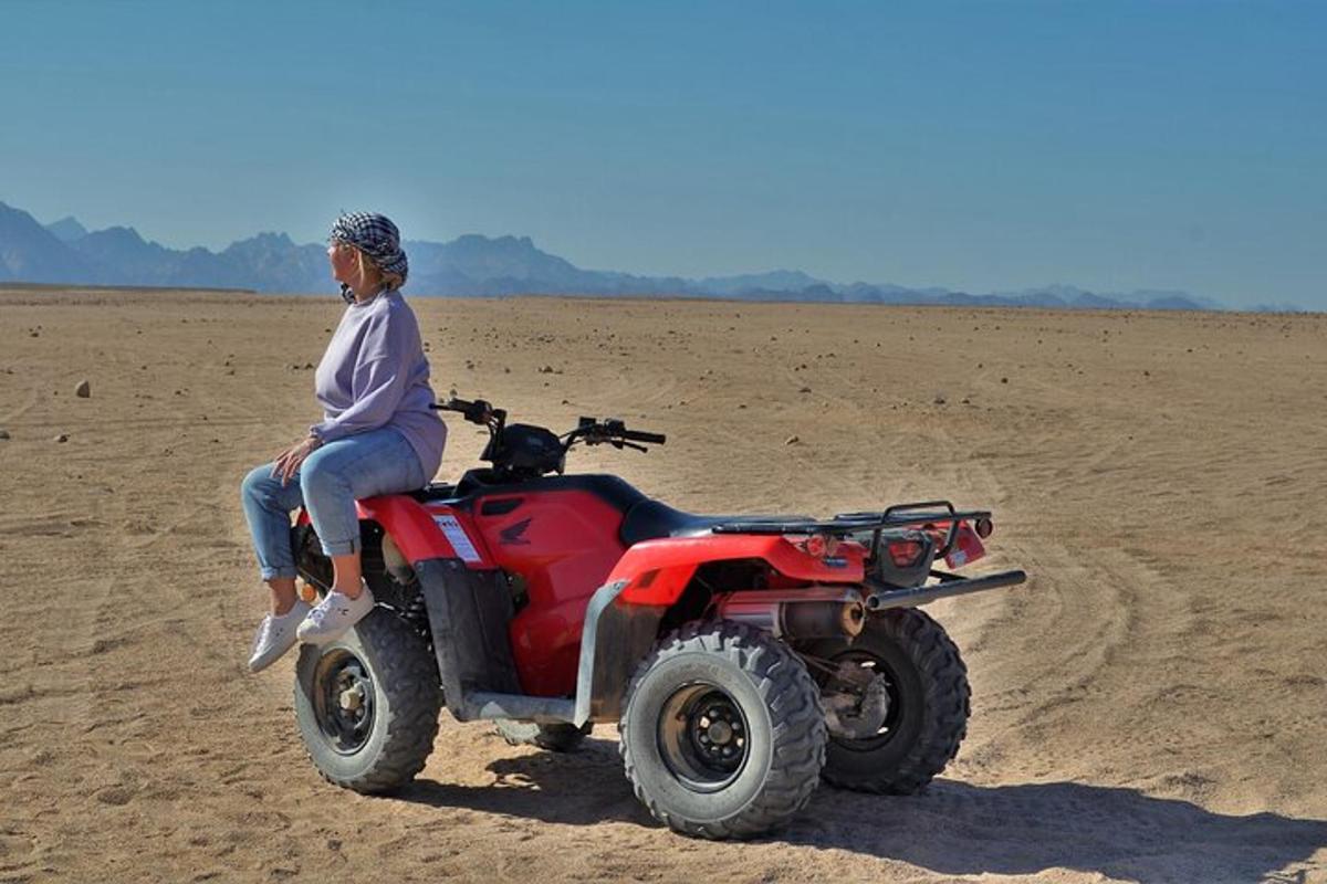 isang babaeng nakaupo sa isang pulang atv sa disyerto