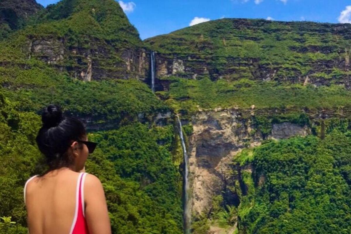 a woman standing on a cliff looking at a waterfall