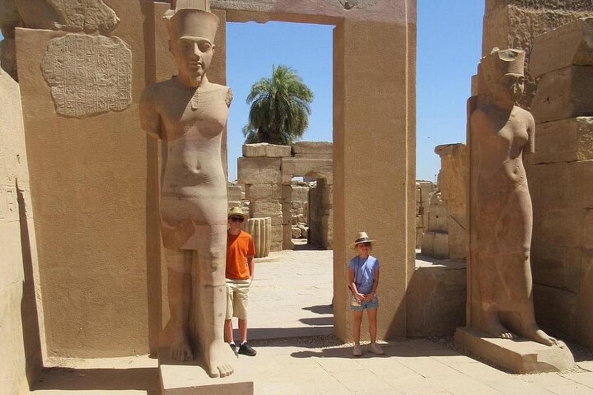 Dos niños de pie junto a una estatua en un edificio.