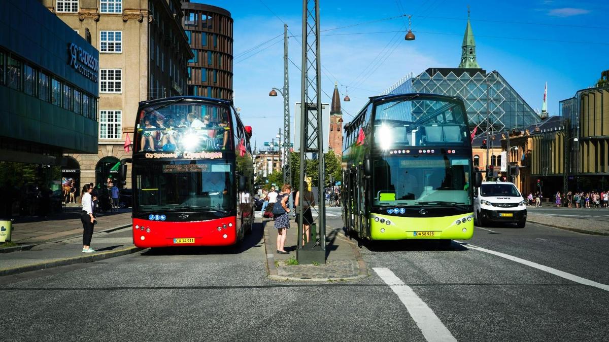 Dos autobuses de dos pisos circulando por una calle de la ciudad