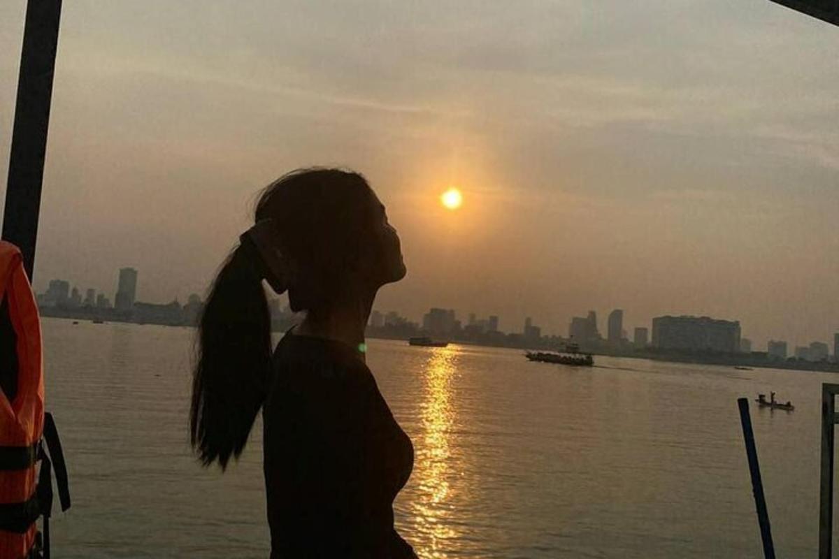 een vrouw die naast een watermassa staat met de zonsondergang