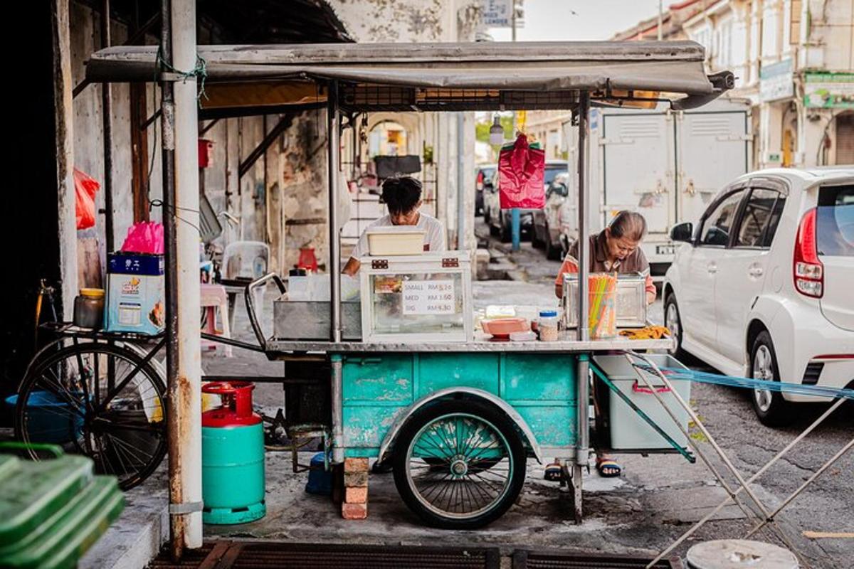 a food cart on a street with two people cooking food