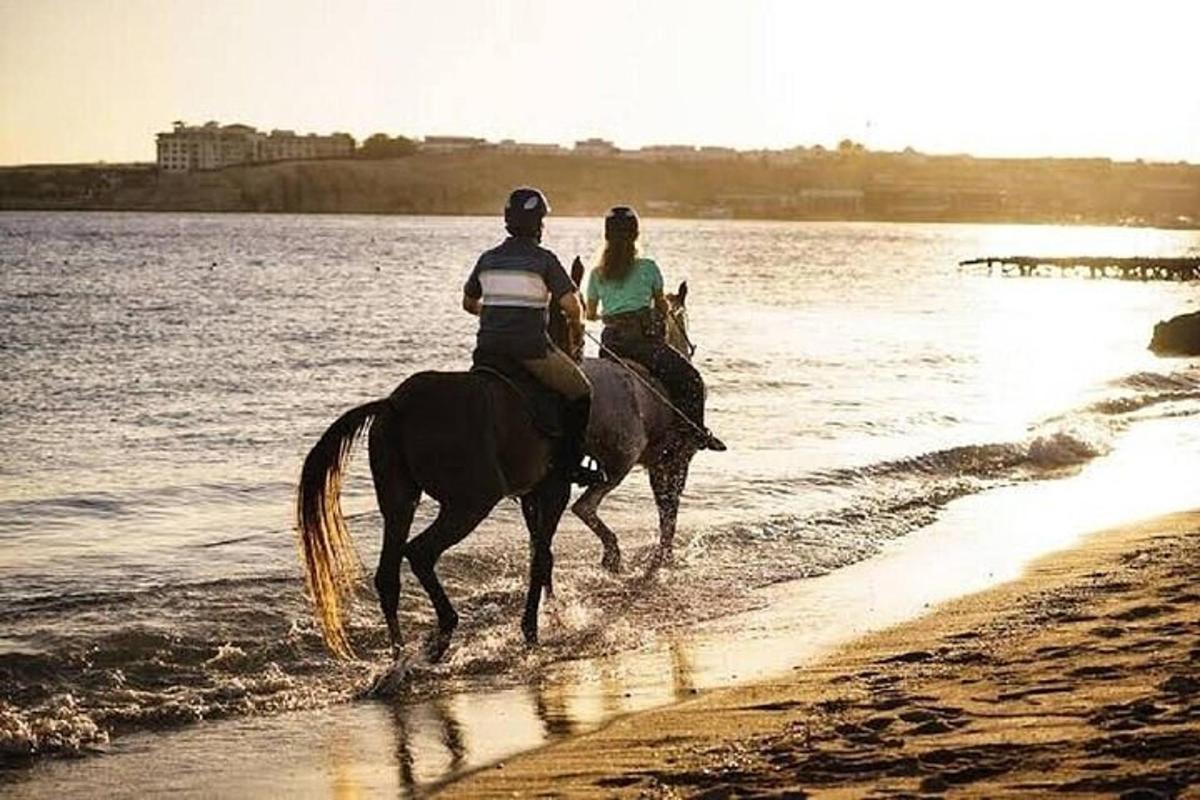 dwie osoby jadą konno po plaży