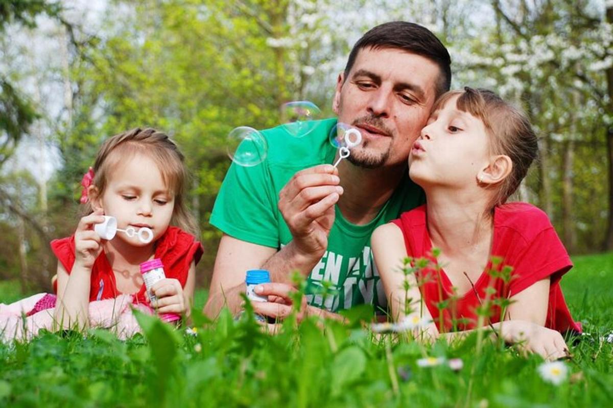 a man and two children laying in the grass with toothbrushes