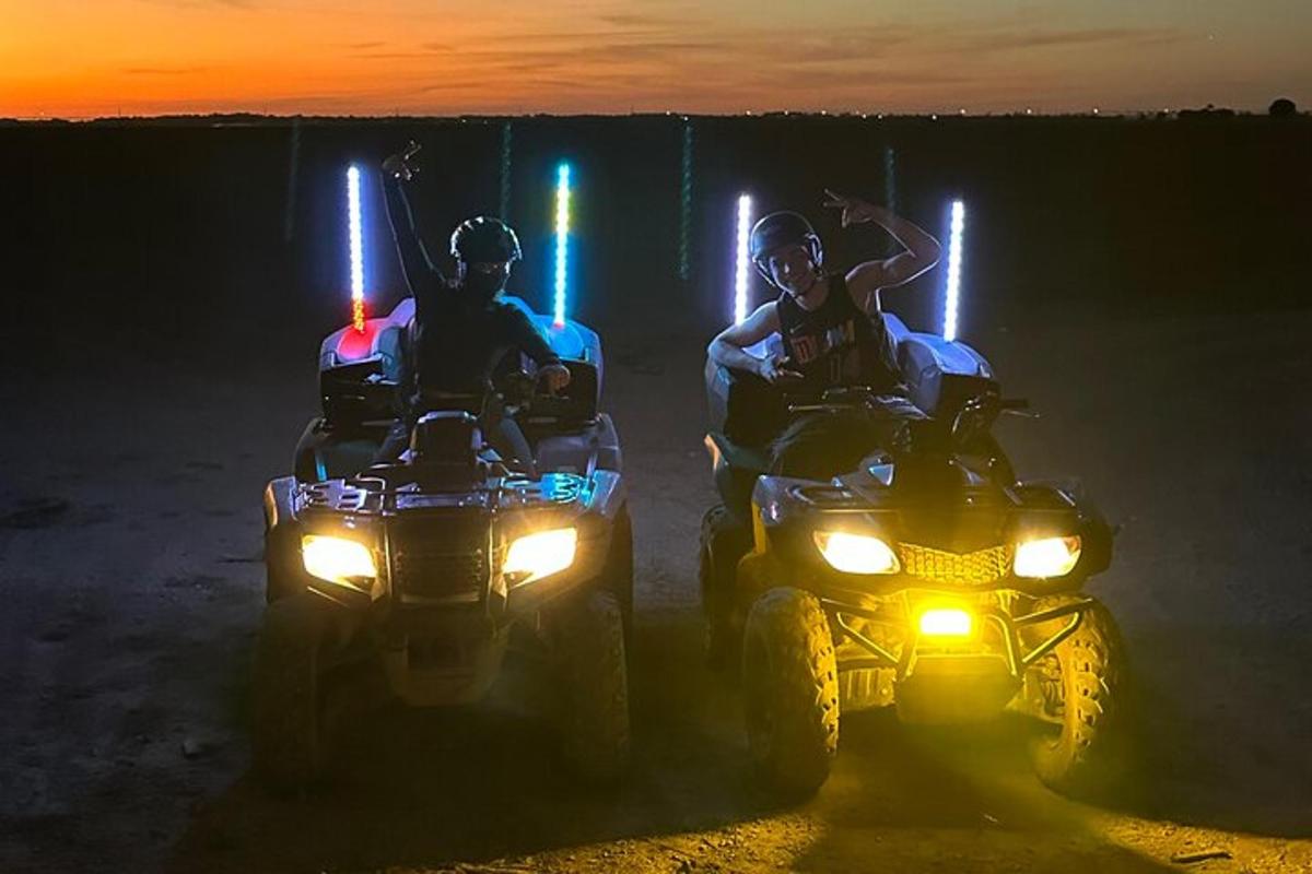 duas pessoas andando de quadriciclo na terra à noite
