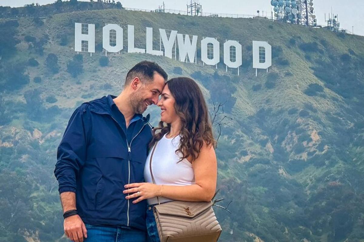seorang lelaki dan seorang wanita berdiri di hadapan papan tanda hollywood