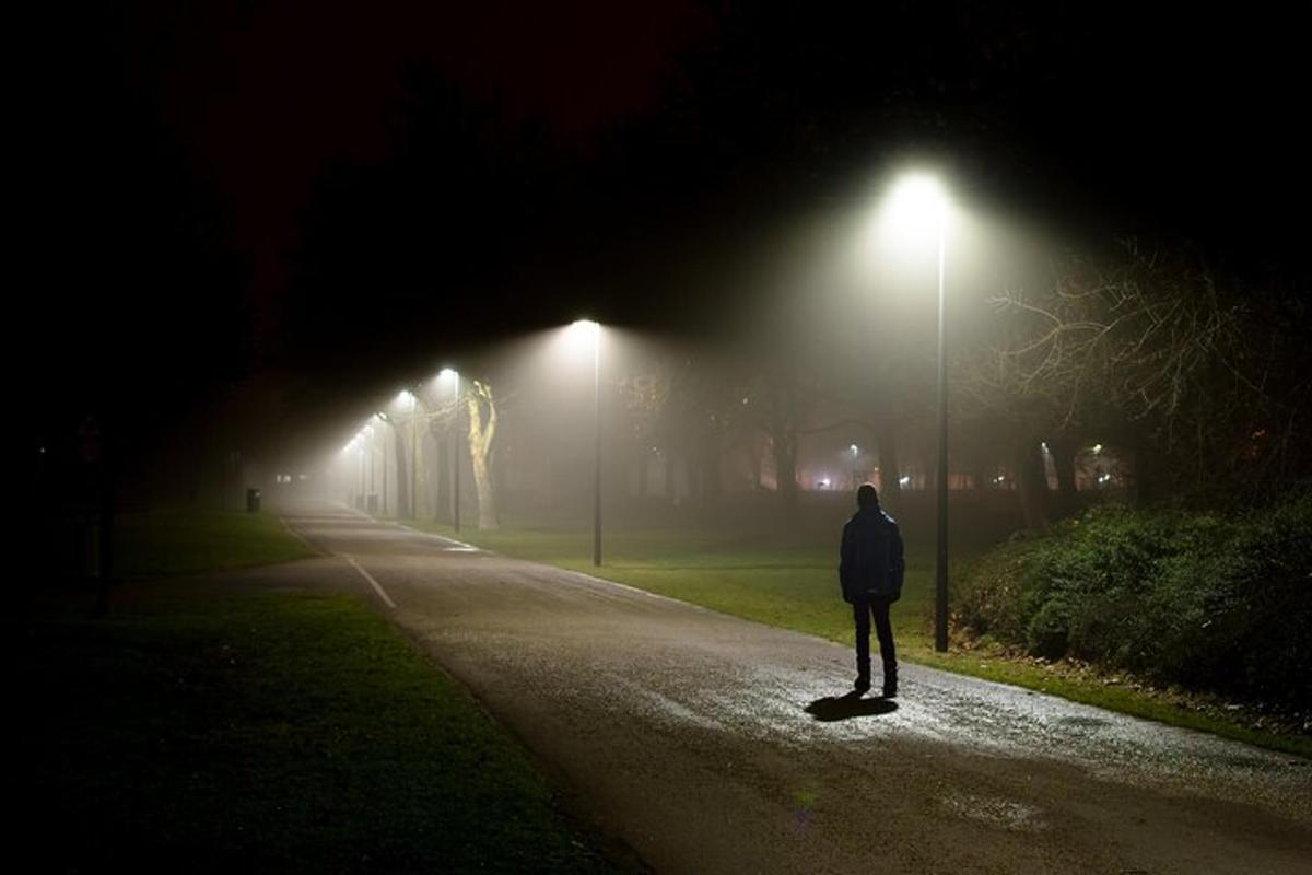 un uomo in piedi in mezzo a una strada di notte