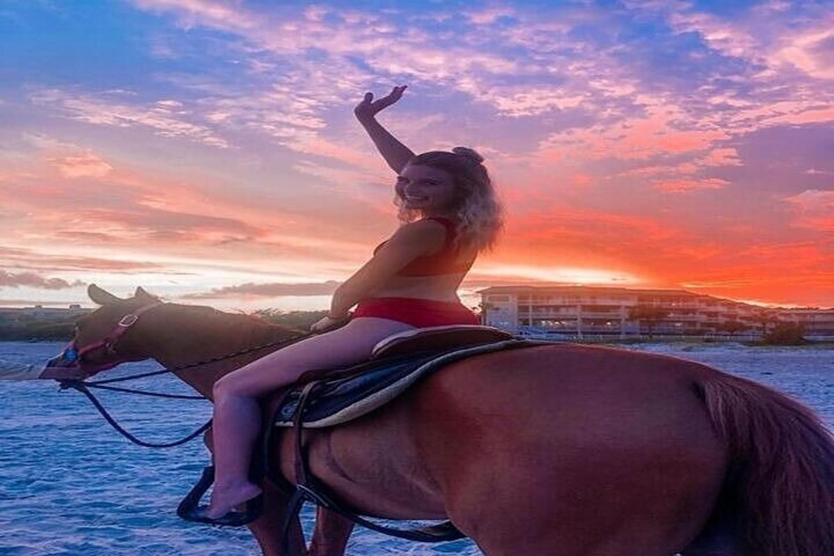 una donna è seduta su un cavallo sulla spiaggia