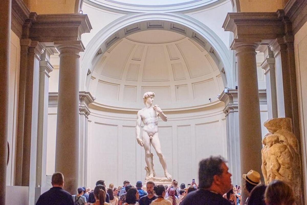 Una multitud de personas mirando una estatua en un museo.
