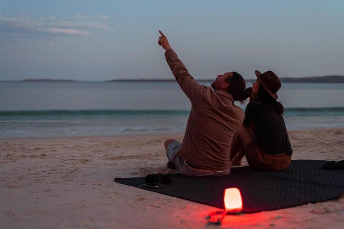 a man and a woman sitting on the beach with a candle