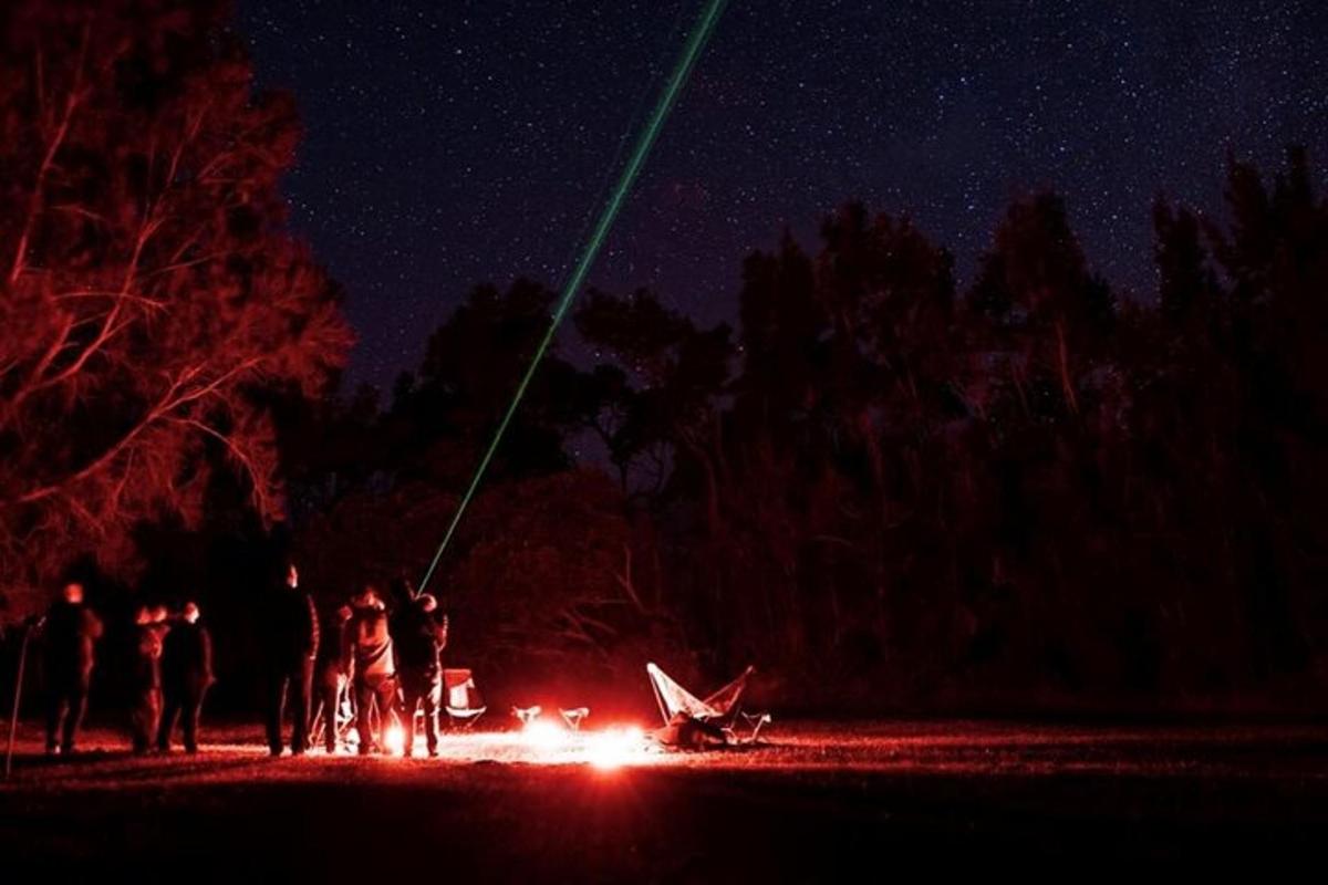 a group of people standing around a fire at night