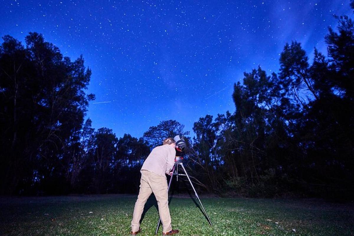 a man is holding a telescope in a field at night