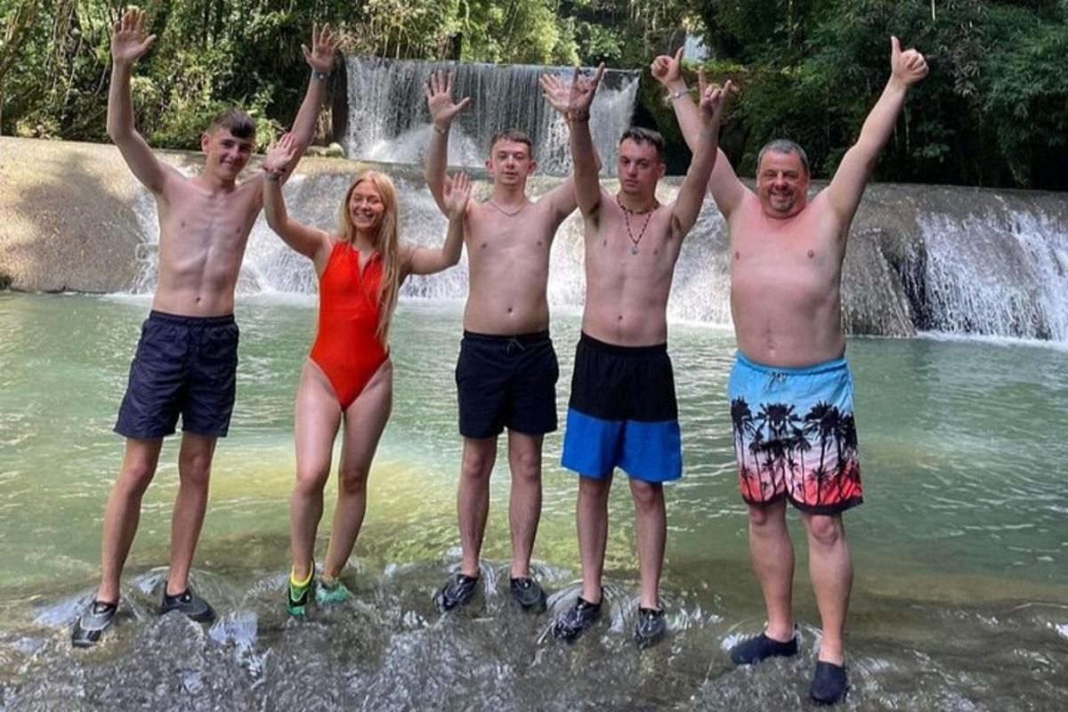 un grup de persones dempeus a l'aigua davant d'una cascada