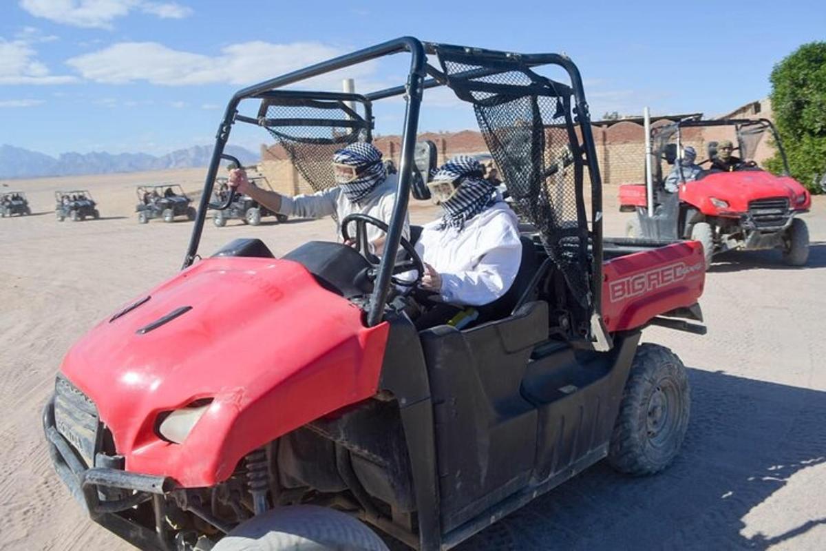 dua orang menaiki atv merah di padang pasir