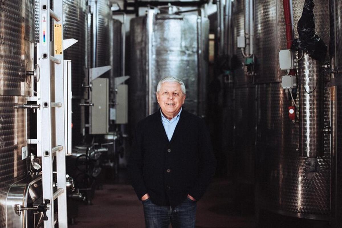 an older man is standing in a wine cellar