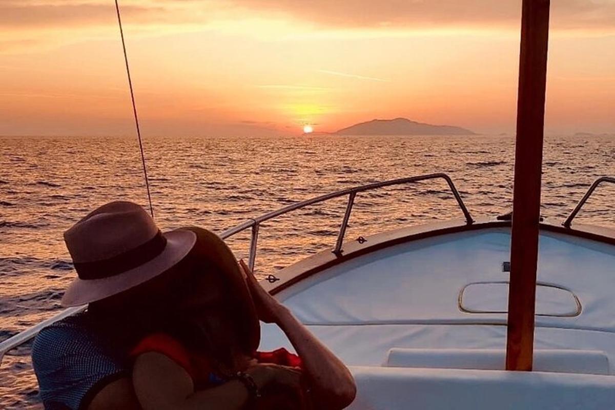 a woman sitting on a boat watching the sunset