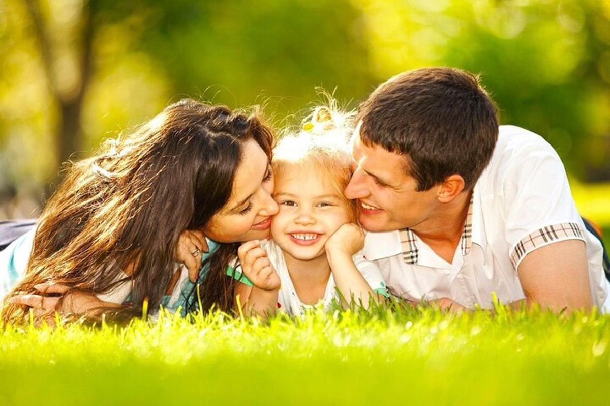 uma família deitada na grama com uma garotinha