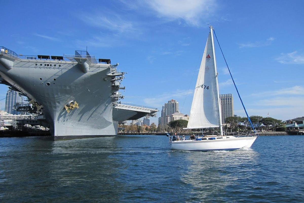 a sailboat in the water next to a cruise ship
