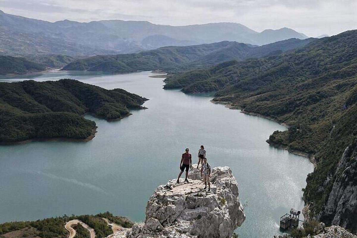 due persone in piedi in cima a una roccia che domina un fiume