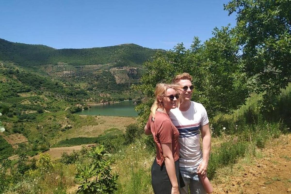 un uomo e una donna in piedi su una collina che domina un lago