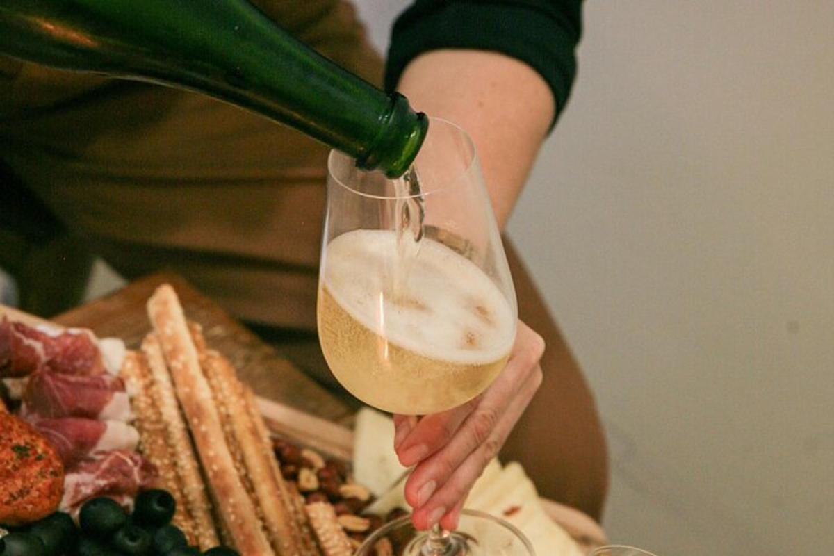 o persoană își toarnă un pahar de vin