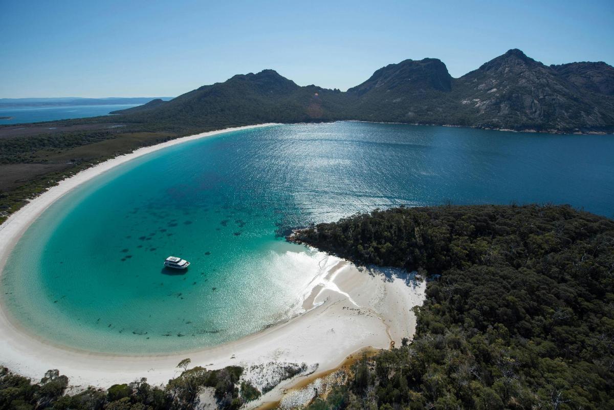 an aerial view of a beach with a boat in the water