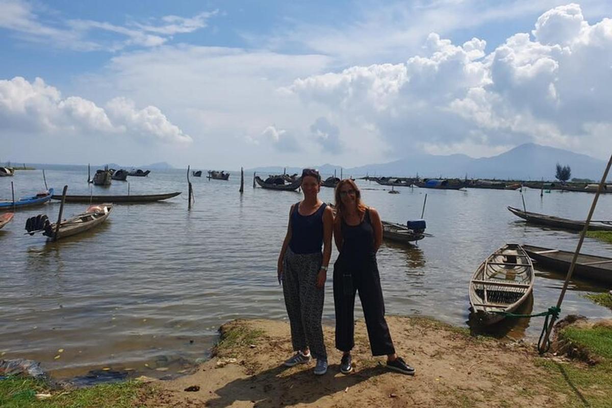 duas mulheres em pé perto da água com barcos