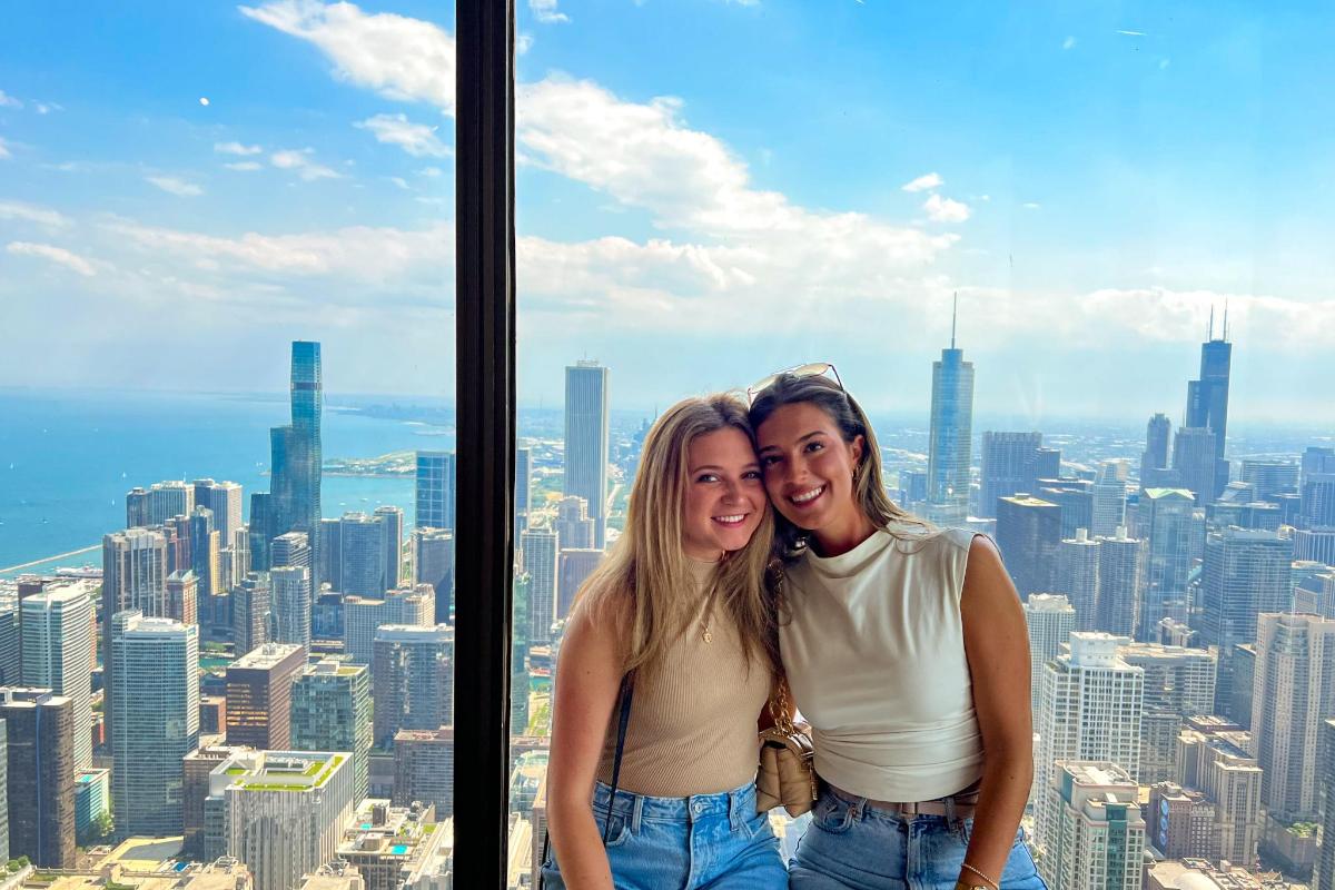 two women posing for a picture at the top of a skyscraper