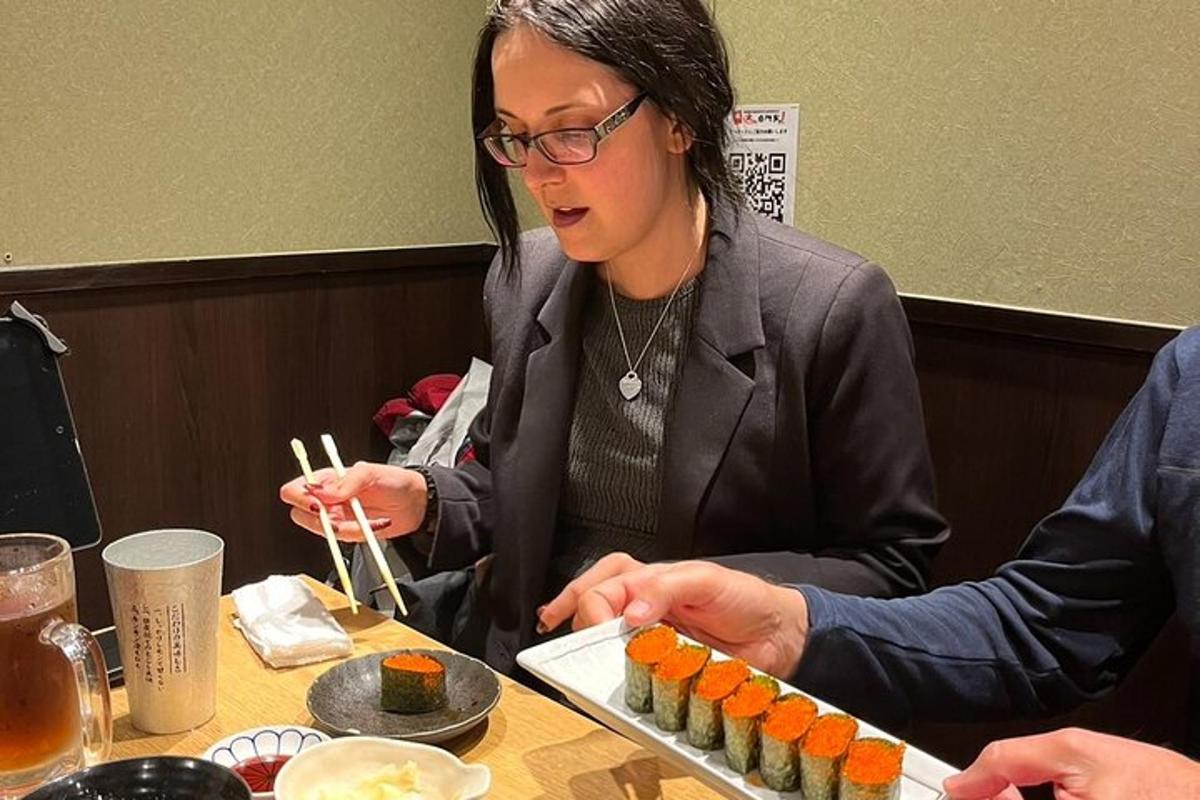 seorang wanita duduk di meja makan sushi dengan penyepit