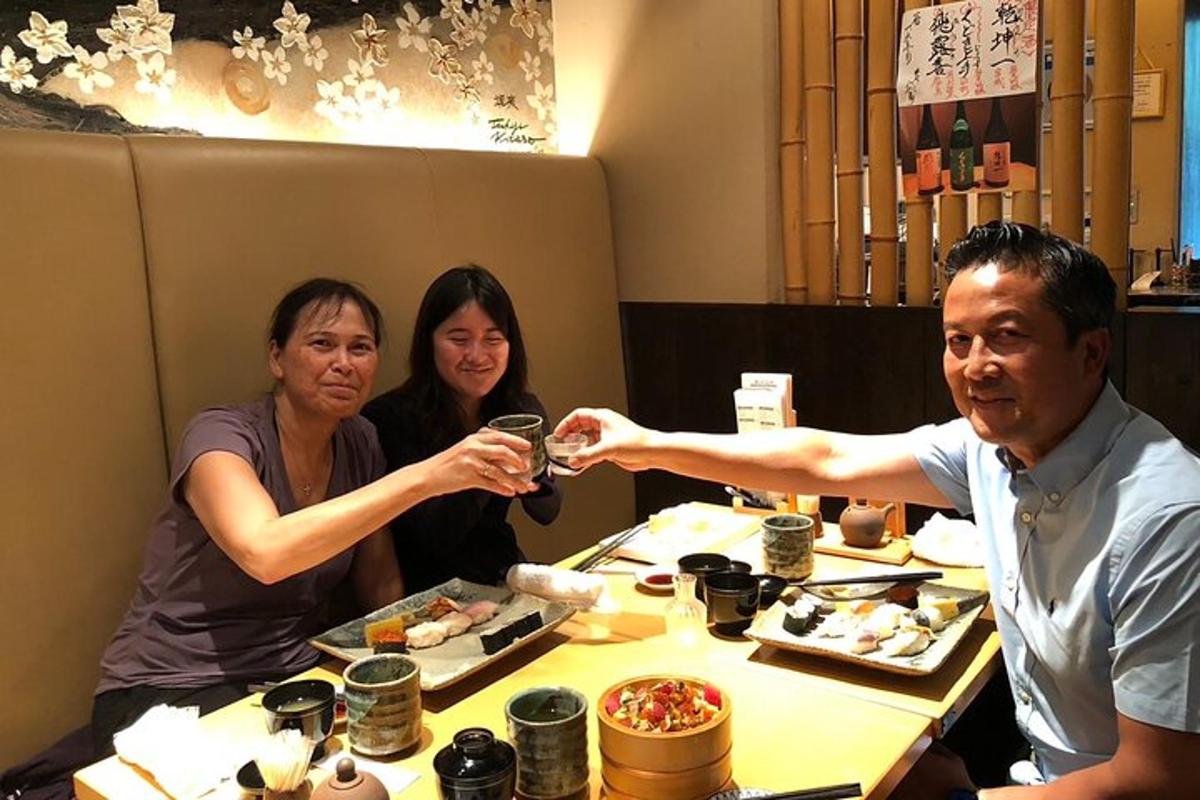 seorang lelaki dan dua wanita duduk di meja sambil minum wain