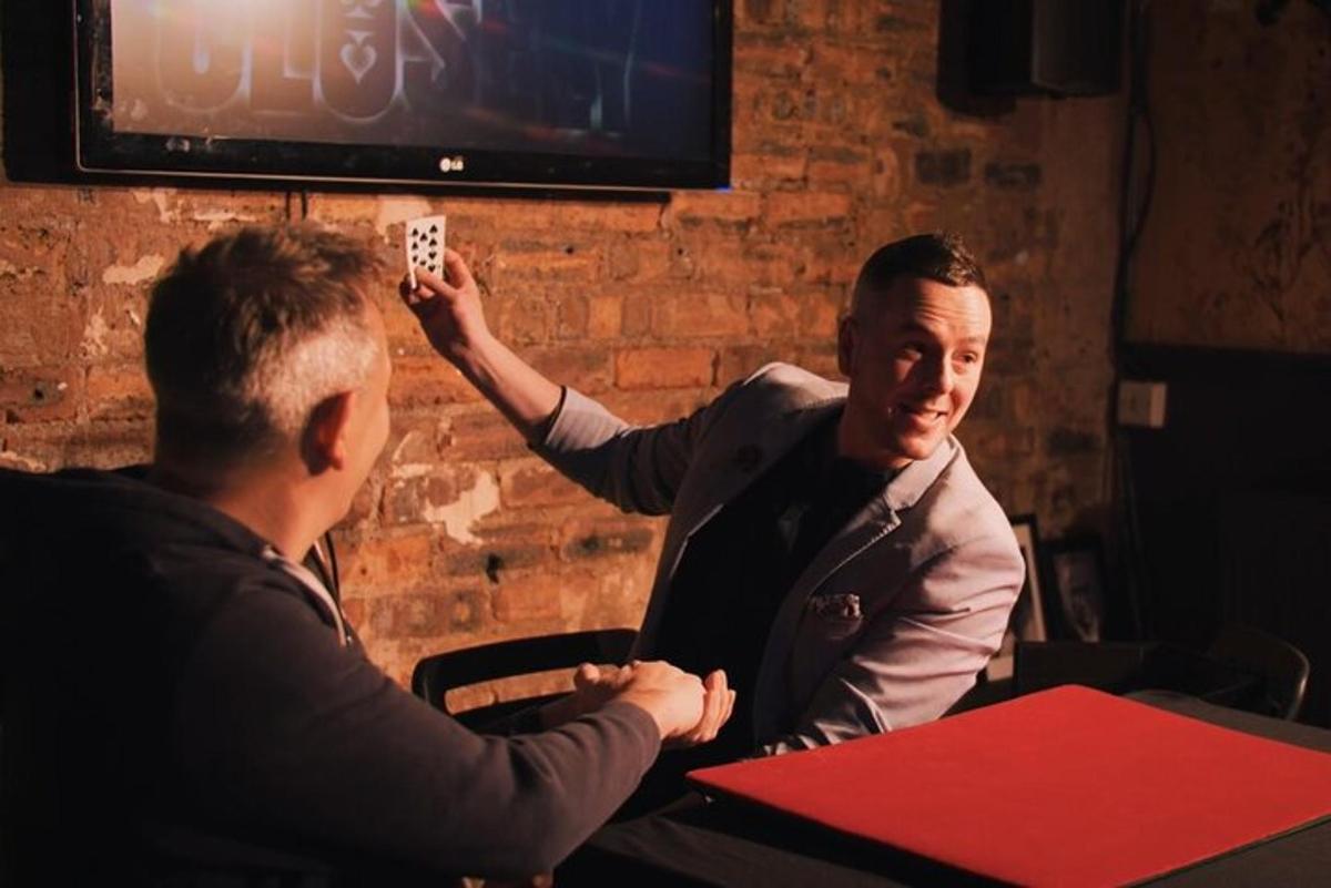 two men sitting at a table with a man holding a remote control