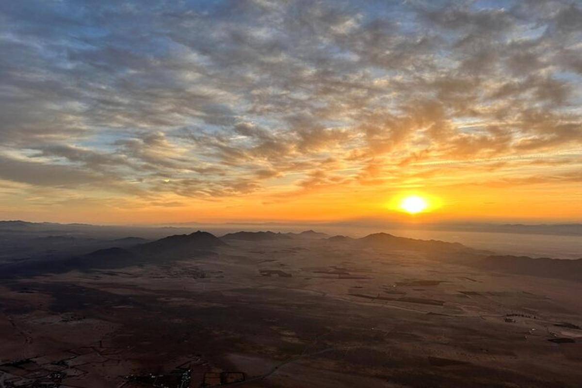un tramonto sulle montagne con il sole nel cielo